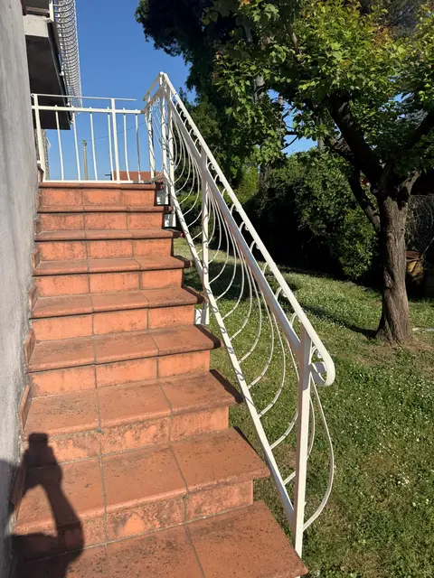 Ringhiera in ferro battuto di una scala esterna riverniciata di bianco