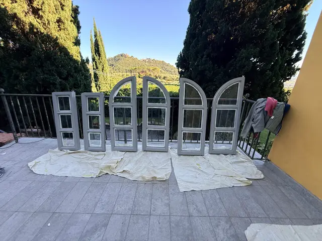 Persiane e infissi ad arco verniciati di grigio chiaro in asciugatura