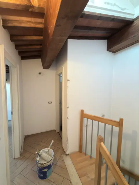 Corridoio con travi in legno a vista e pareti tinteggiate di fresco