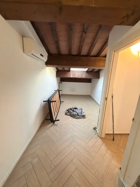 Mansarda con travi in legno e pareti bianche tinteggiate